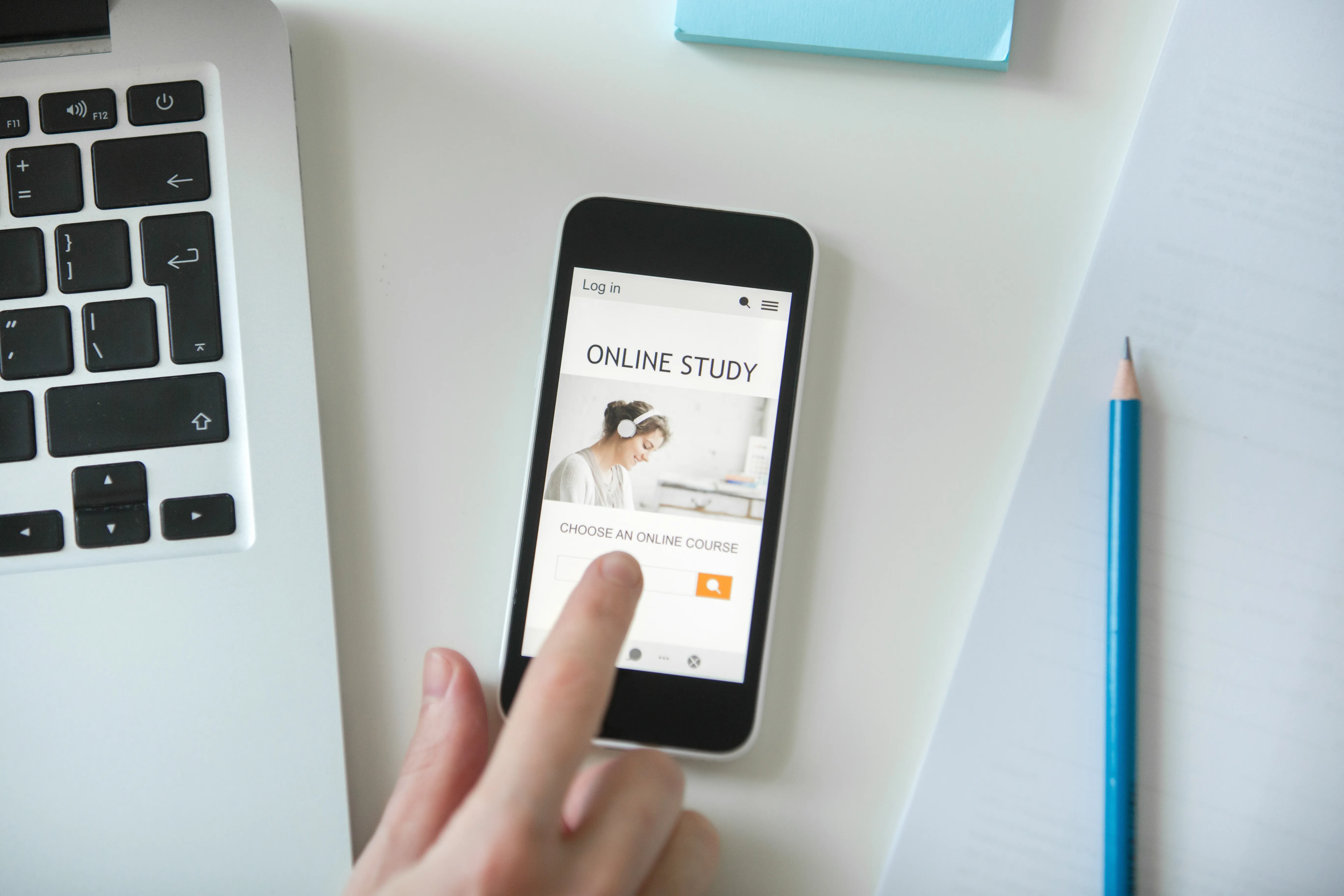 White office desk with hand touching mobile phone